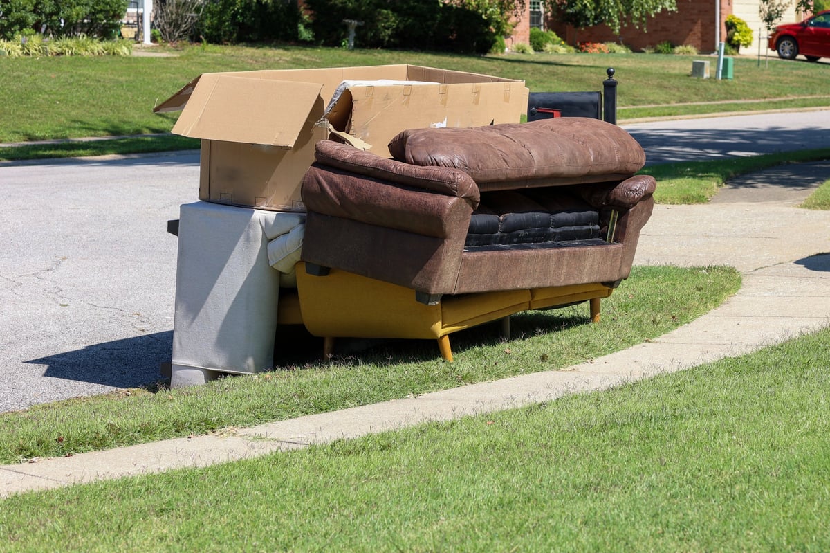 Worker disposing of old furniture on a sidewalk