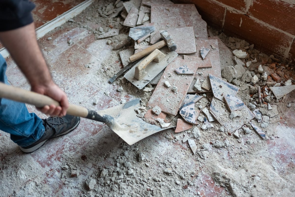 Worker picking up debris with a shovel after demolition